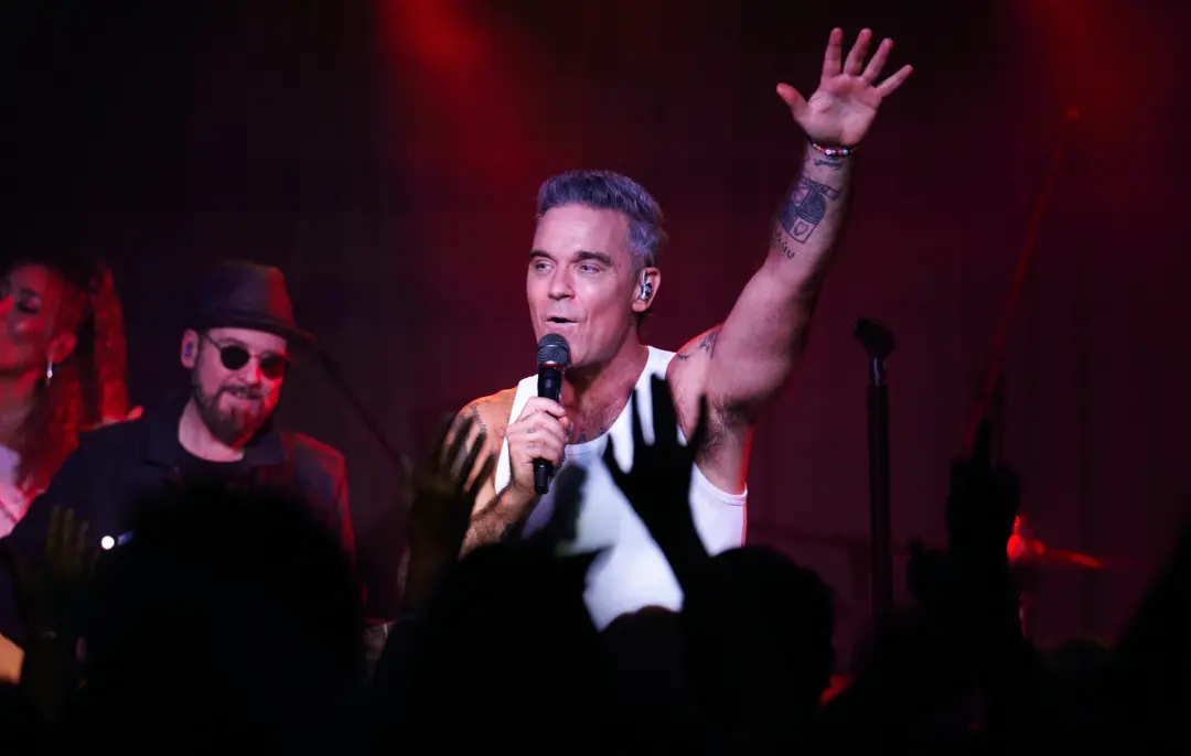 Robbie Williams fez uma apresentação surpresa para uns 30 a 40 fãs na Buenos Aires, fora do Faena Hotel. É um gesto de …