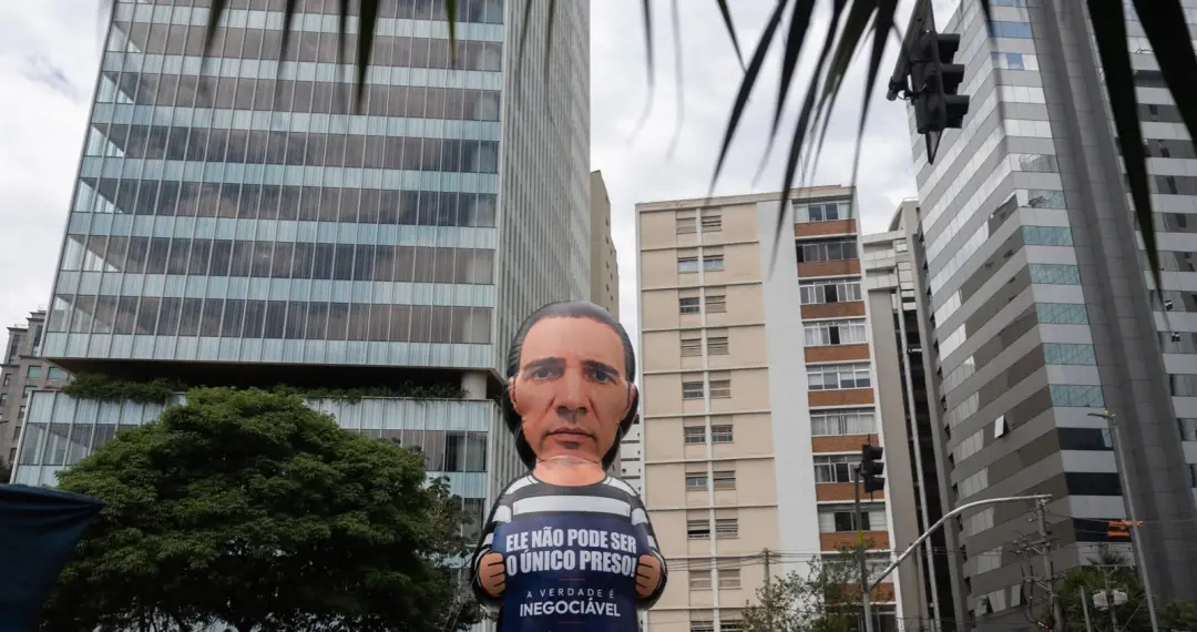 Julie Milck colocou um boneco de Daniel Vorcaro na Faria Lima pedindo que Brasília responda porque ele é o único preso.…