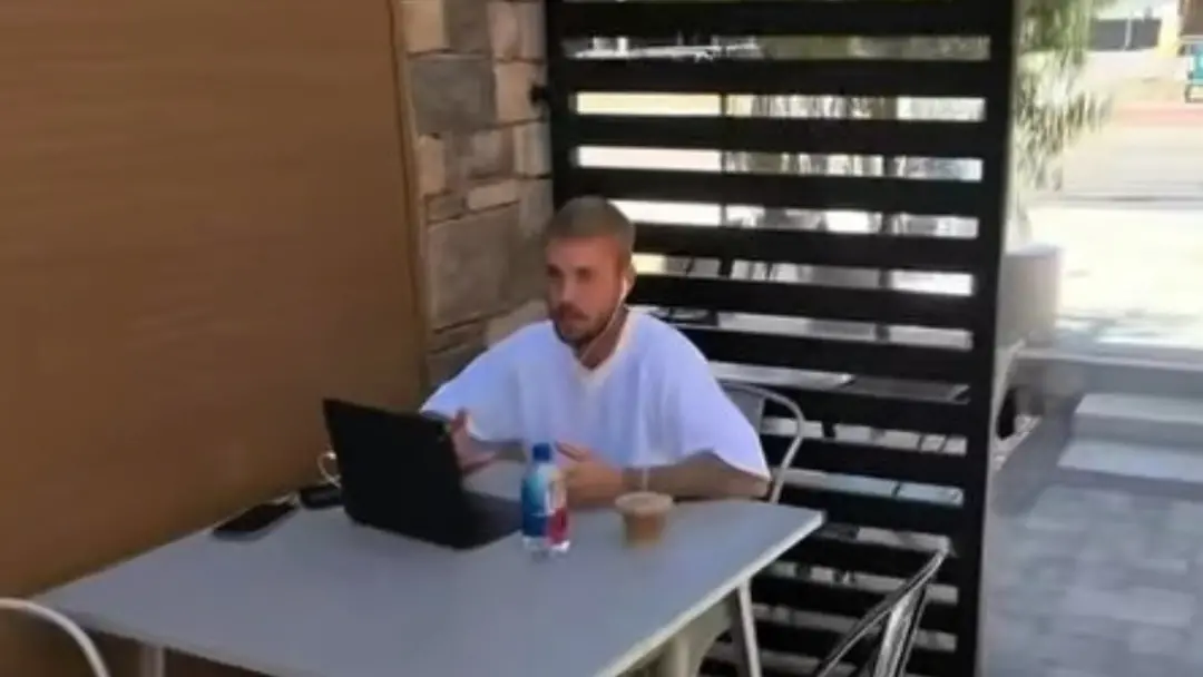 Um cantor pop famoso trabalhando no notebook em um beco fora de cafeteria, sem segurança visível. Achei irado ver essa …