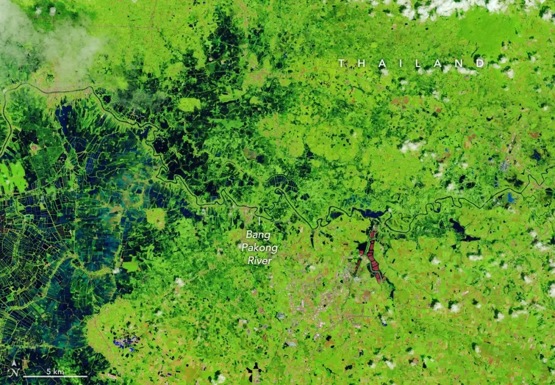 Águas de enchente dominam grande parte de uma área agrícola na Tailândia. A água cobriu vastos campos ao lado de um rio…